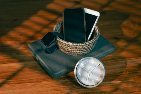Evening digital detox with devices in basket and analog clock in warm light