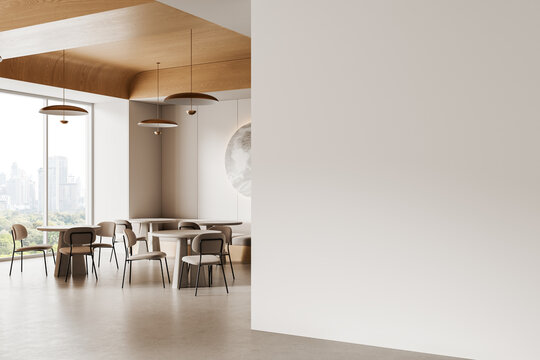 Modern minimalist interior with dining tables and chairs beside large blank wall ideal for mockup or poster design display in bright daylight room. 3D Rendering