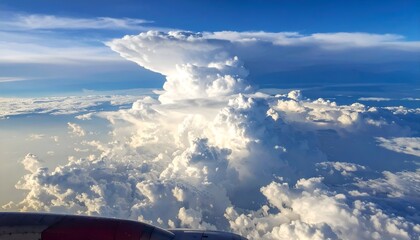 Dramatic cumulus cloud formation towers above soft, rolling clouds against a brilliant blue sky