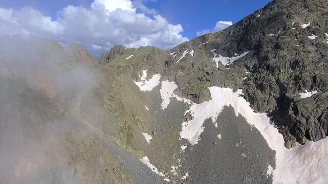 Aerial timelapse of sharp rocky alpine mountain peaks in summer across high altitude USA ranges. Rugged cliffs and exposed ridgelines reveal dramatic geology under clear blue sky.
