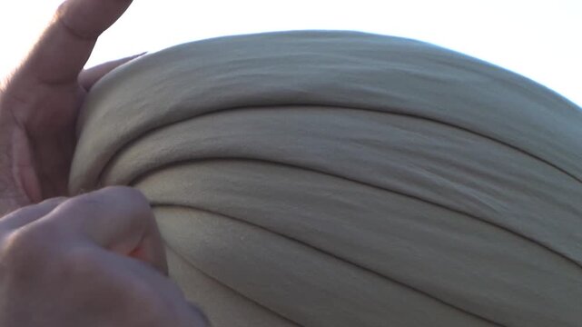 closeup shot of sikh man tying turban on his head.