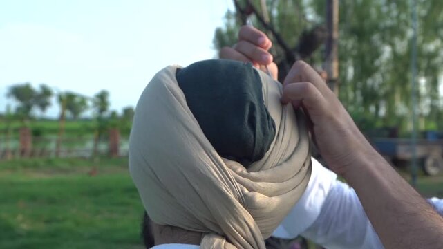 closeup shot of sikh man tying turban on his head.