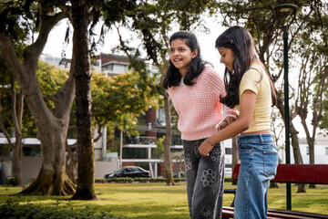 Obraz premium Teen Sister Helping Younger Sister on Rollerblades in Park