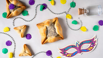 Purim hamantaschen cookies arranged with masquerade masks and confetti on light background festive Jewish holiday concept
