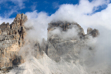 Fototapeta premium Clouds embrace the Tre Cime di Lavaredo from a mountain path