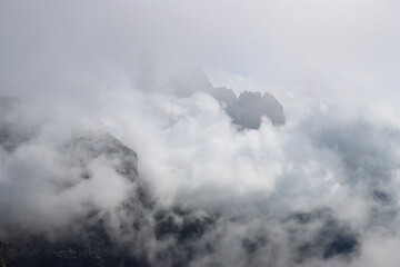 Dolomites peaks shrouded in alpine mist and clouds