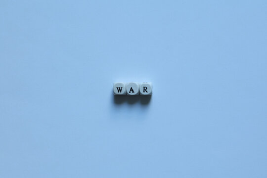 The word &ldquo;war&rdquo; spelled with letter tiles on a cool white background, representing conflict, tension, global issues, and geopolitical concepts.