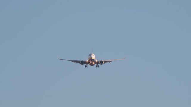 Dramatic video of a commercial passenger jet on final approach. The airplane flies closer, culminating in a powerful low-angle shot as it passes overhead against a clear blue sky.