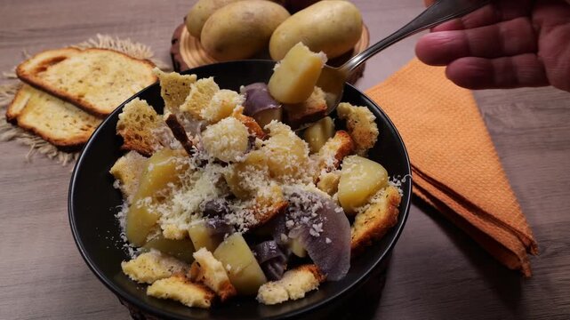 Persona che con un cucchiaio prende la zuppa dal piatto per mangiarla