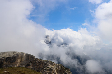 Dolomites spires covered by thick white clouds