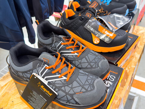 Ponte Nelle Alpi, Italy - January 27, 2026: Kaptur brand athletic shoes displayed on wooden shelf with tags visible, showcasing gray and orange color scheme in a retail setting