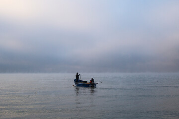 Minimalist Seascape of Two Fishermen in a Misty Calm Sea at Dawn
