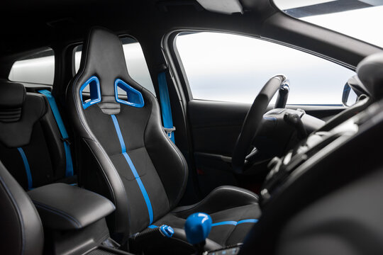 Sporty wagon car interior with leather bucket seats at night near illuminated wall. Driver's seat in focus and rear rows in the background.