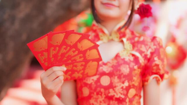 During the Chinese New Year celebration, a young woman in a traditional red qipao (cheongsam) holds a red envelope.