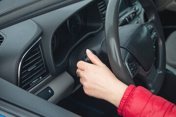 Female hand is adjusting headlight switch in car.