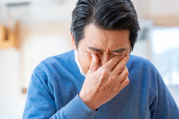 目を抑えるシニア男性