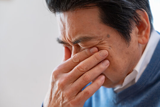 目を抑えるシニア男性