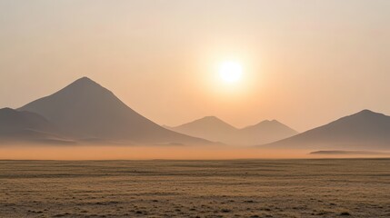 Distant mountains obscured by dusty orange haze under a warm glowing sunset sky