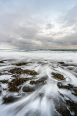 Obraz premium Waves crashing on the beach in Varangerfjord on a cloudy winter day