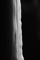Moody monochrome shot of an extinguished candle with a wisp of smoke. Noise grain add on the post