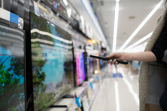 家電量販店でテレビを選ぶ女性の手