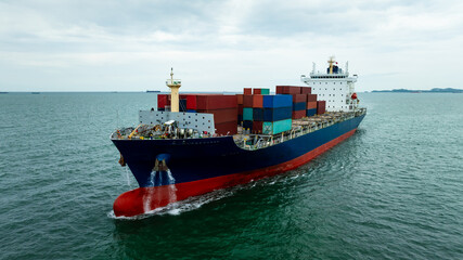Fototapeta premium Aerial front view of large cargo container ship sailing in open sea with bow wave