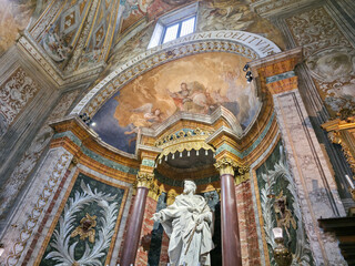 Fototapeta premium A richly decorated interior of the Oratory of St. Joseph in Urbino, featuring a central statue, marble walls, golden columns, and detailed frescoes