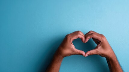 Obraz premium Two hands come together to form a heart shape against a soothing blue background, embodying love, unity, and affection in a warm and inviting manner.