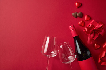 Valentine's day composition of red wine bottle, two glasses, gift box and heart shaped chocolate candies