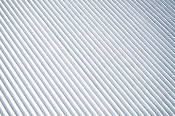 Obraz premium Corduroy snow texture on a freshly groomed ski slope, showing clean parallel ridges and detailed winter snow structure, ideal as background or texture for winter sports themes.