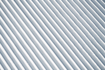 Obraz premium Corduroy snow texture on a freshly groomed ski slope, showing clean parallel ridges and detailed winter snow structure, ideal as background or texture for winter sports themes.