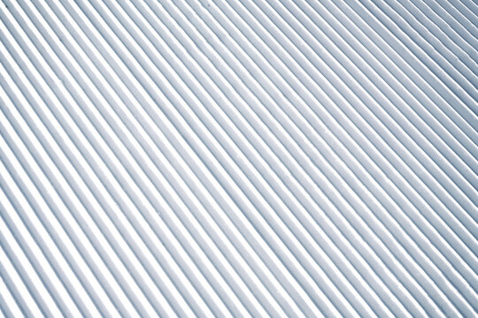 Corduroy snow texture on a freshly groomed ski slope, showing clean parallel ridges and detailed winter snow structure, ideal as background or texture for winter sports themes.