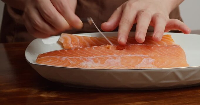 Preparing the salmon: Remove the bones from the fillet with a piercer. Season the fresh salmon fillet on a wooden table with sea salt and add refined sugar.