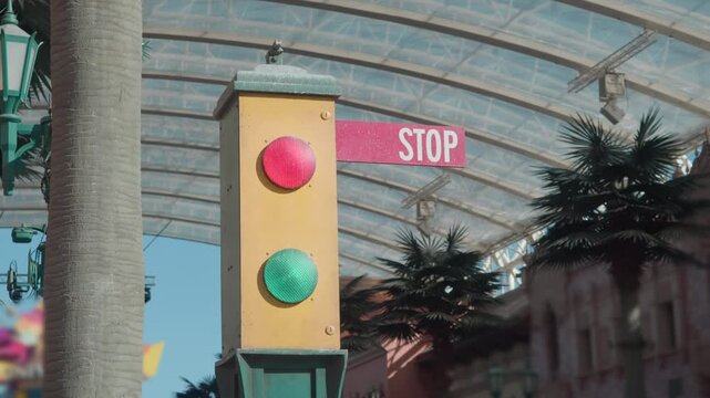 Close up retro traffic signal shows mechanical sign reading STOP, then message flips to GO to allow movement at themed street location.