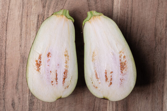 The interion of an eggplant cut in half on a wood cutting board