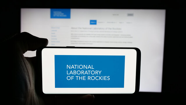 Stuttgart, Germany - 01-24-2026: Person holding cellphone with logo of US National Laboratory of the Rockies (NLR) on screen in front of webpage. Focus on phone display.