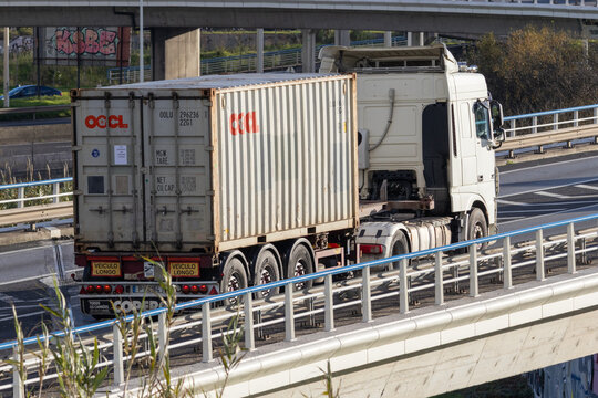 White truck transporting shipping container on highway bridge