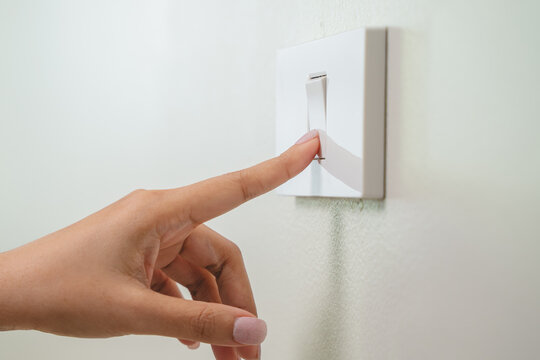 Save energy concept, Close-up person turn off switch off light on the wall