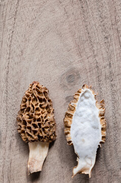 A morel mushroom split in half on a wood table, copy space above
