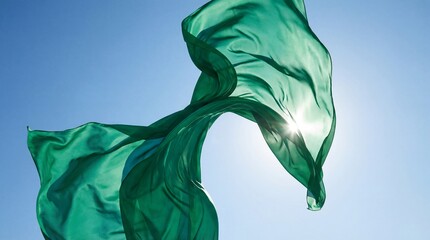 A flowing green silk fabric illuminated by sunlight against a clear blue sky, symbolizing nature and freedom