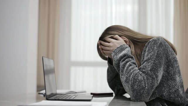 Stressed depressed woman crying at her desk with a laptop