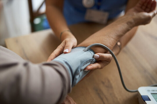 Close up of unrecognizable female nurse measuring blood pressure of a woman during her home visit.