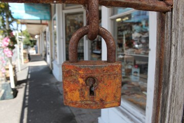 Naklejka premium Rusty Padlock Hanging on Store Closure Sign After Business Hours