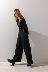 Editorial fashion model walking forward in modern black jumpsuit, posing confidently in minimalist studio. Contemporary style, strong attitude, lifestyle and copy space. © Cumhur