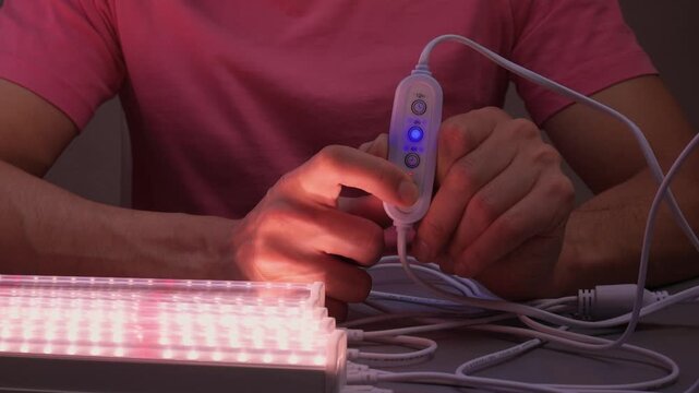 Hands finetuning hydroponic system, Adjusting grow lights for indoor plant growth, Technician meticulously configuring lighting and controls for indoor plant cultivation system