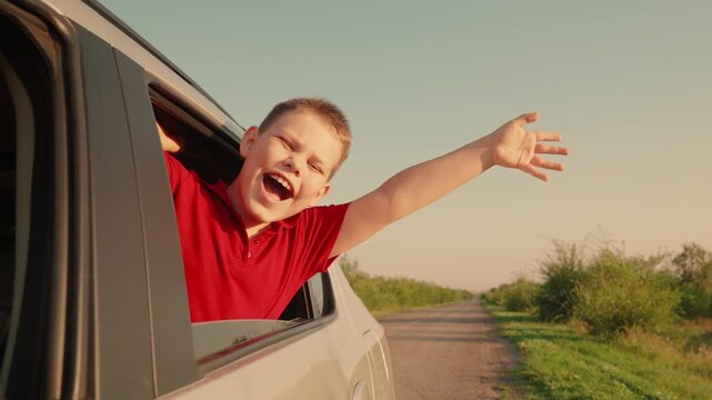 child boy looks out car window, joy face child kid, childhood dream, wind hair, sun child leans out window catches wind with hand, car rural road, outstretched hand forward, fresh wind blows his hair