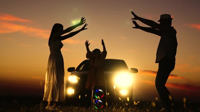 Happy close-knit family dancing at sunset. Man woman child girl kid against of car with lights on dancing to music. Freedom of spirit, personality, boundless happiness, enjoyment of life at sunset.