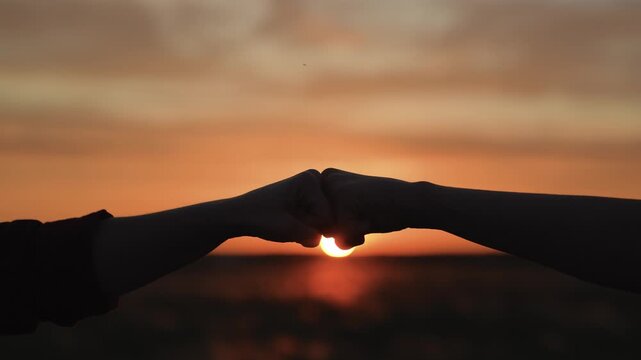 Hands clashing fists brofist at sunset. Bump clash of two fists. Confrontation competition. Gesture of giving respect approval. Teamwork friendship partnership working together at agricultural farm.