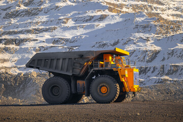 Obraz premium Massive yellow mining truck in snowy open-pit coal mine winter scene