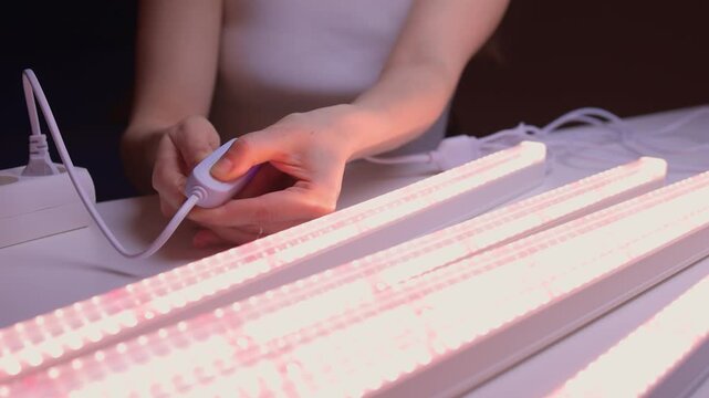 Hands finetuning hydroponic system, Adjusting grow lights for indoor plant growth, Technician meticulously configuring lighting and controls for indoor plant cultivation system